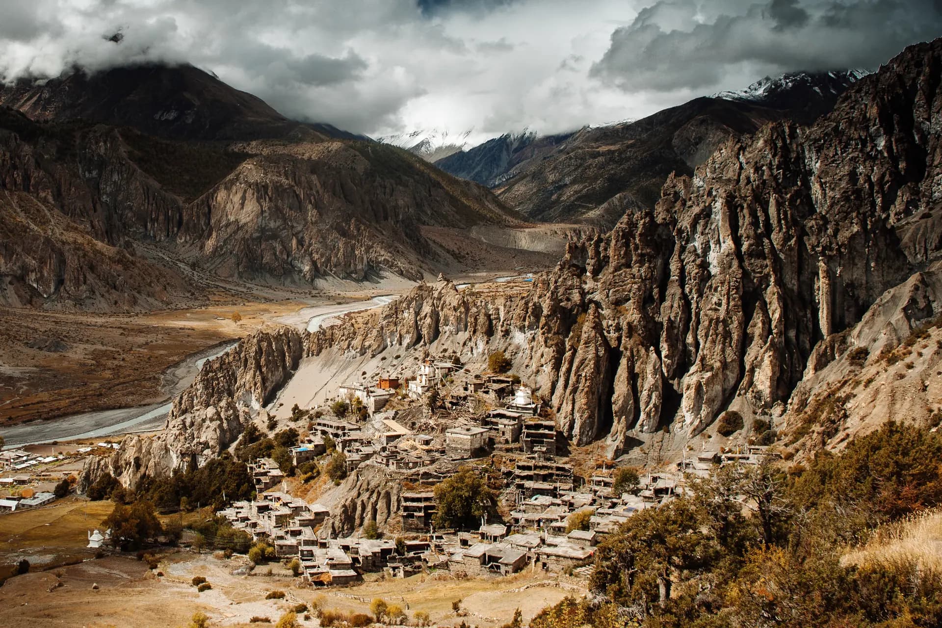 Stone houses of a Manang village beneath eroded cliffs and the Annapurna range
