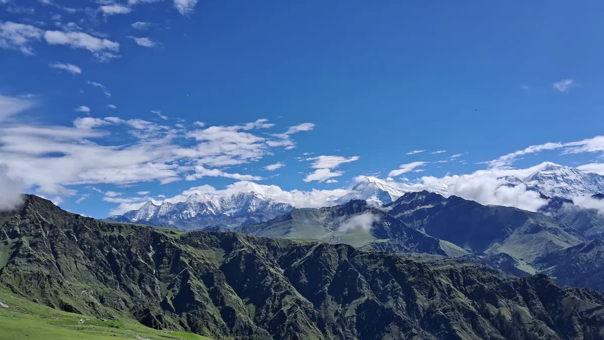 Green high pastures and forested ridges of Dhorpatan below a line of snow peaks