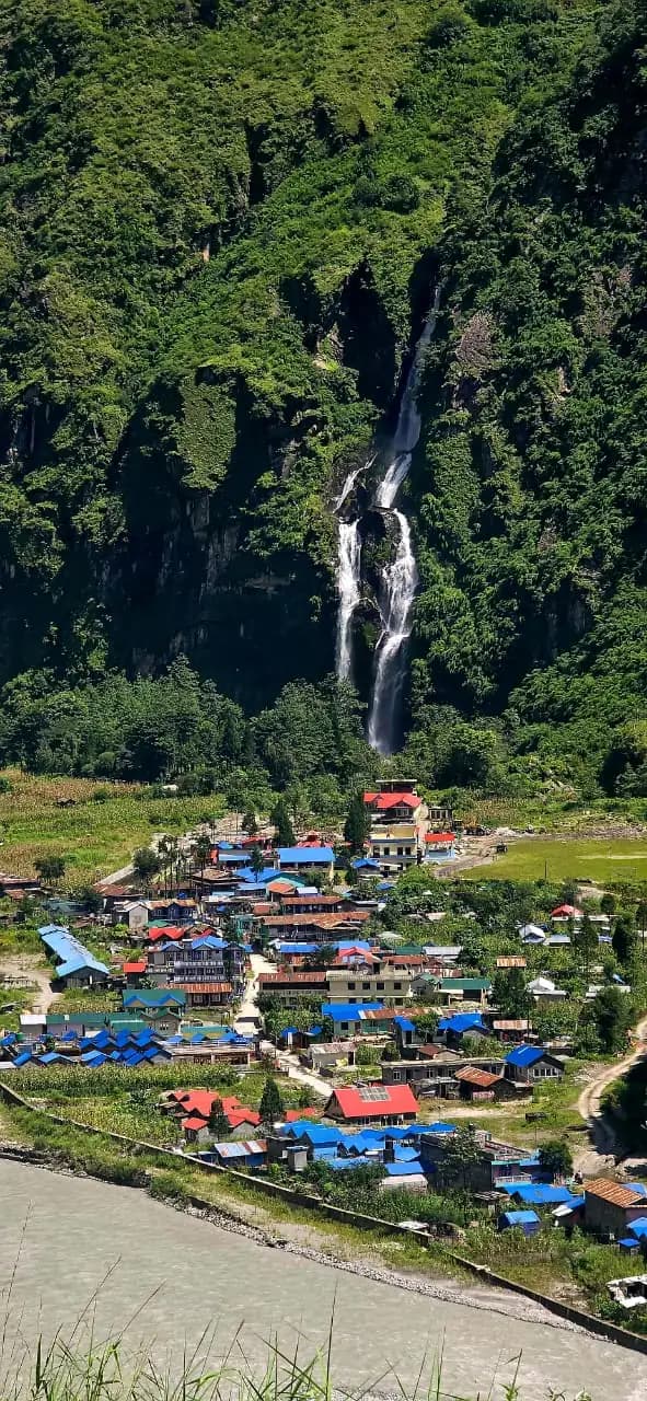 Tal village beneath a waterfall on the wooded Marsyangdi valley wall