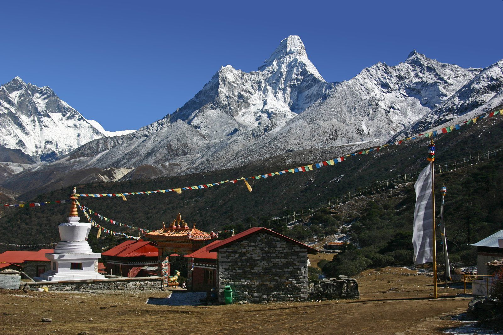 Tengboche Monastery below Ama Dablam, with a white stupa and lines of prayer flags strung across the foreground