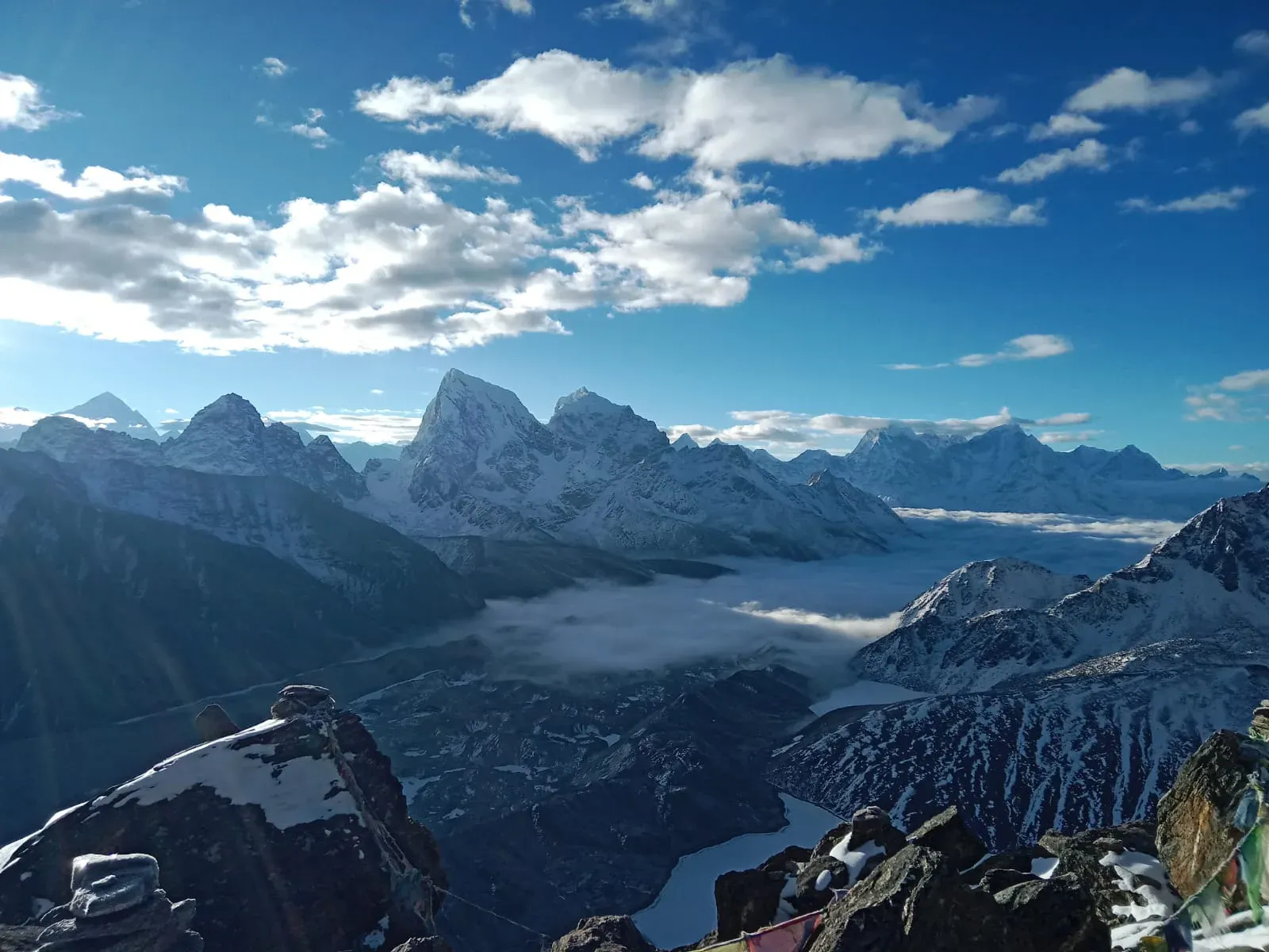 Snow-covered peaks and a high valley in the Everest region under a blue sky.