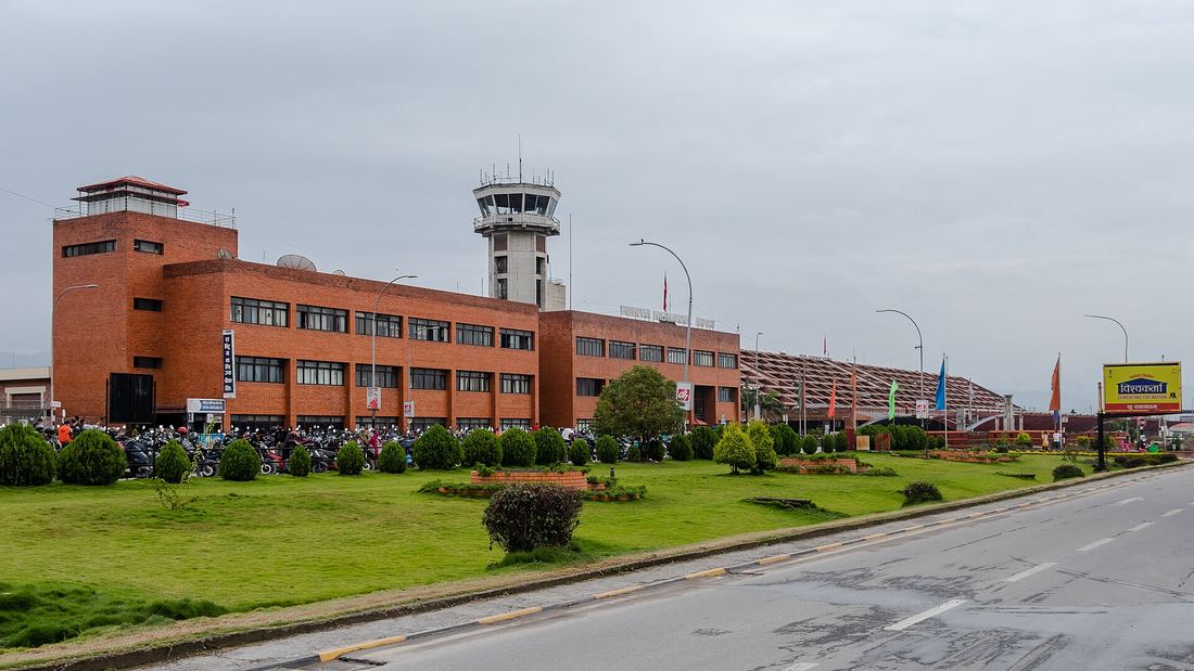 The terminal building at Tribhuvan International Airport in Kathmandu, with its patterned brick facade and arriving passengers outside