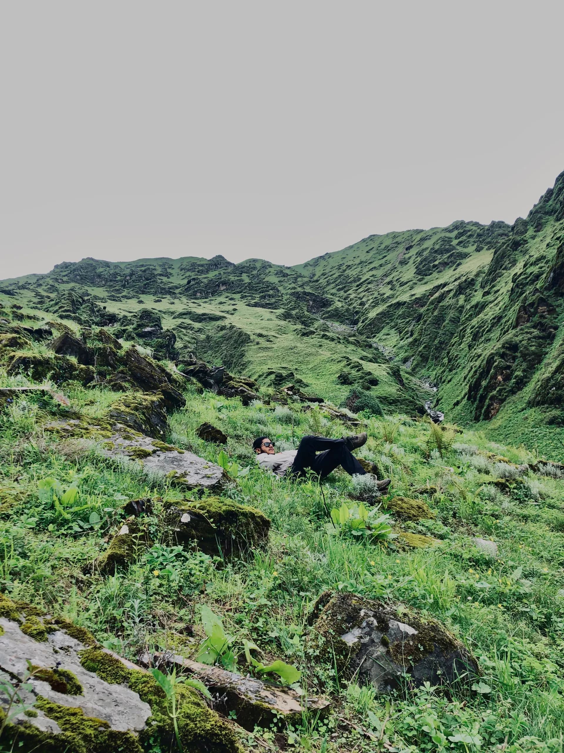 Trekker resting among mossy boulders on the trail below Garpachheda